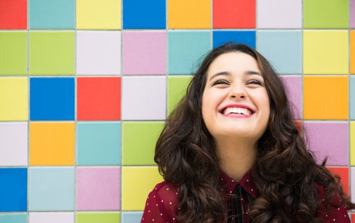 Happy Girl Laughing Against Colorful Tiles: Joyful Moment